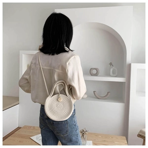 Detail of round handmade woven crossbody bag with cotton rope texture and wooden button