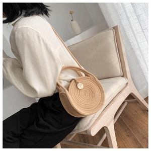 Detail of round straw bag showing spiral woven texture and versatile shoulder strap