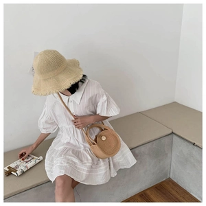 Detail of summer straw accessories with wide-brim hat, round bag, and striped dress