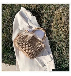 Detailed texture of straw woven handbag with white lace bow on white blazer