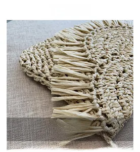 Detail showing the intricate handmade straw weave and fringe tassels on a summer beach bag