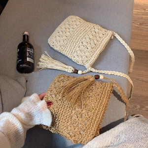 Détail de sacs en paille crochetés main avec motifs floraux évidés et longues franges