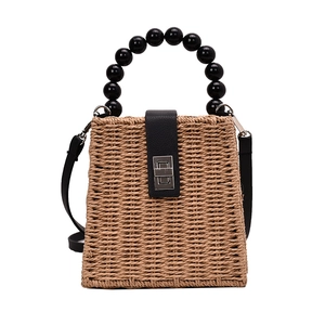 Handwoven straw handbag with black beaded handle and metal twist lock for beach vacation