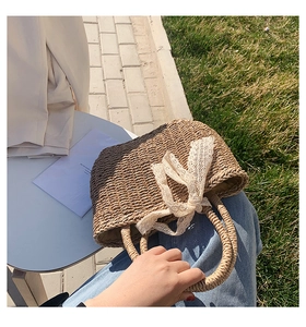 Close-up of woven straw tote bag featuring a delicate beige lace bow decoration