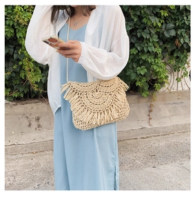 Detail of handmade straw crossbody bag featuring long bohemian tassels and woven texture