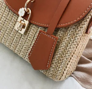 Dettaglio della borsa in paglia con finiture in pelle, chiusura in metallo e fiore