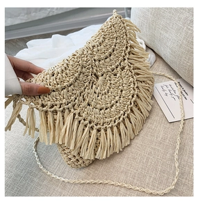 Detail of handmade straw crossbody bag with decorative fringe and bohemian woven texture
