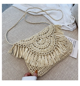 Close-up of bohemian straw woven bag featuring elegant hanging fringe tassels