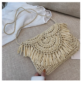 Detail of handmade straw bag featuring elegant paper rope tassels and woven strap textures
