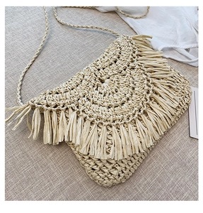 Detail of handmade straw crossbody bag featuring fringe edges on a textured background
