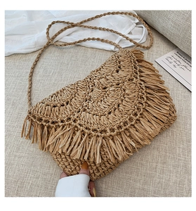 Close-up of handmade straw crossbody bag with long tassel fringe and woven texture