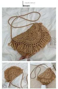 Detail of a brown woven straw bag with handmade tassels and a long shoulder strap