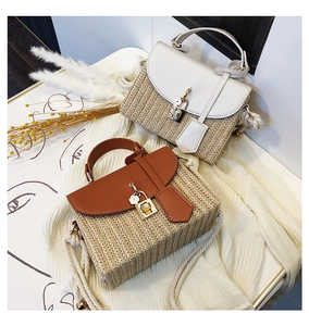 Detail of hand-woven straw bags with leather flaps and metallic flower pendant