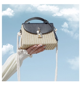 Detail of straw woven bag with black leather flap and rope strap against a blue sky