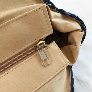 Détail du sac de plage tressé bleu avec fermeture éclair métallique et doublure kaki