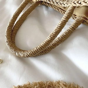 Dettaglio della trama a spirale e fodera marrone di una borsa a secchiello in paglia