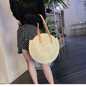 Detail of a large round straw woven tote bag with premium brown leather straps on shoulder