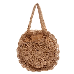 Detail of hollow woven straw tote bag with dual handles and fabric lining for summer beach use