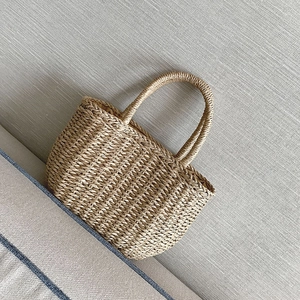 Dettaglio della borsa in paglia intrecciata a mano con texture naturali e manici a U