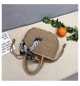 Dettaglio borsa in paglia intrecciata con foulard a pois verdi e chiusura a coulisse