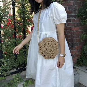 Detail of a handmade woven hexagonal straw shoulder bag with an intricate hollow pattern