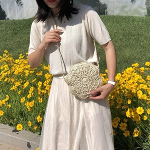 Detailed close-up of a handcrafted floral knit crossbody bag in creamy white finish