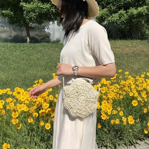 Detail of beige hand-woven hollow bag featuring floral crochet pattern in a flower field