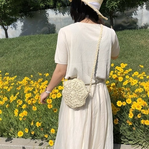 Detail of cream woven shoulder bag with floral knit pattern in a sunny outdoor setting