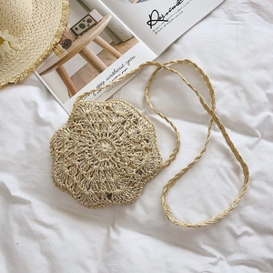 Detail of flower-shaped beige straw woven handbag on white fabric for summer