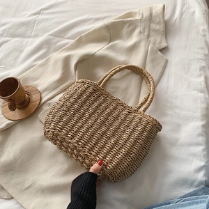 Handwoven straw tote bag for summer beach holidays placed on a neutral linen fabric