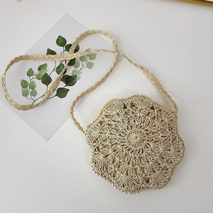 Detail of hand-woven straw tote with hollow sunflower pattern and natural texture