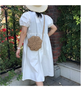 Detail of handmade woven straw crossbody bag with floral cut-out texture for summer