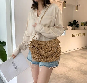 Handmade khaki straw shoulder bag with fringe tassel detail on a lifestyle model