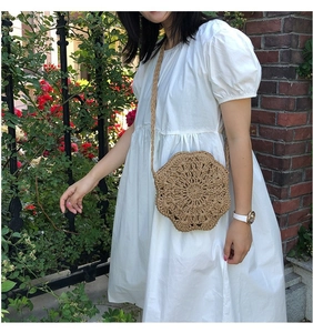 Detail of handmade woven straw bag with hollow floral pattern on red brick background