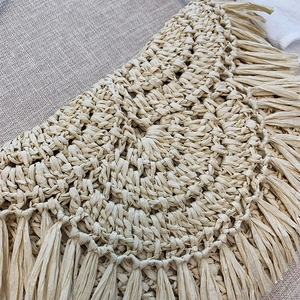 Handmade woven straw beach bag with bohemian tassels and intricate spiral crochet texture