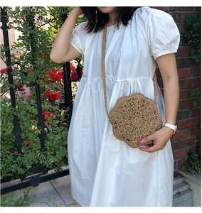 Detail of flower-shaped woven crossbody bag with hollow straw texture and strap