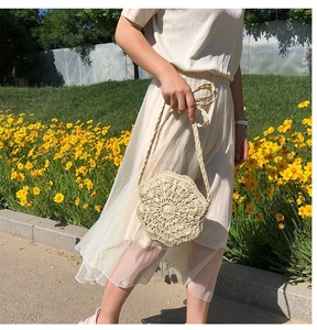 Detailed close-up of handmade off-white floral woven shoulder bag in a garden setting