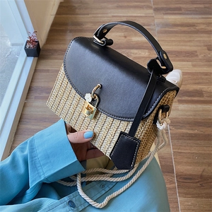 Handwoven straw square handbag with black leather trim and floral gold clasp accent