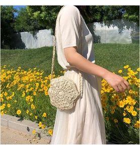 Close-up of beige crochet shoulder bag with floral patterns on a sunny lawn background
