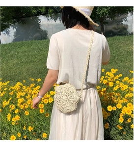 Detailed view of cream hand-woven straw shoulder bag with floral pattern and thin strap
