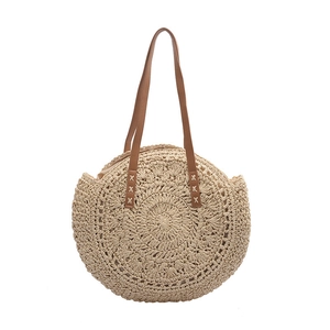 Handmade round straw beach bag with brown leather straps and woven spiral pattern