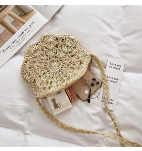 Detailed view of handmade woven straw bag with floral crochet pattern and daily essentials