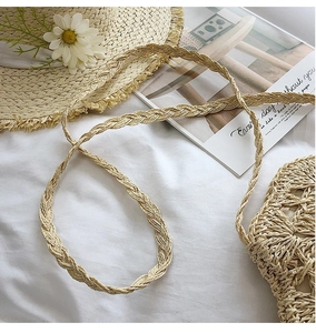 Detail of hand-woven straw bag with hollow knit patterns and a long braided strap