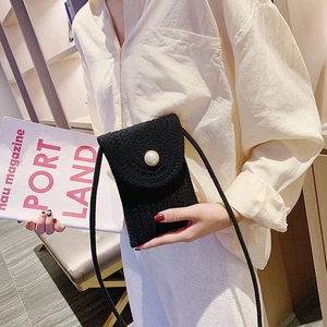 Detail of black woven crossbody phone bag featuring a decorative white pearl clasp