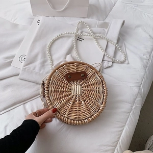 Détail du sac rond en paille avec bandoulière en perles et patch en cuir marron