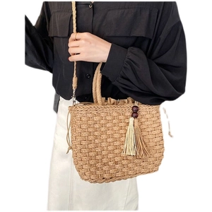 Detail of straw woven handbag featuring wooden beads, tassels, and a drawstring liner
