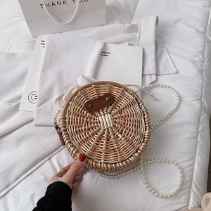 Gros plan détaillé d'un sac rond en paille tressée avec bandoulière en perles et cuir