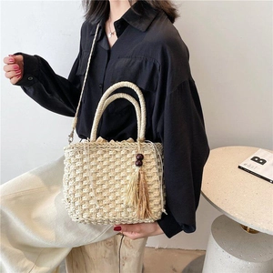 Detail of straw woven handbag with circular handles and beaded tassel accessory