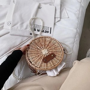 Détail du sac rond en paille avec anse en perles et boucle en cuir marron et métal