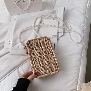 Vue détaillée de la texture du sac en paille tressée et des perles de la bandoulière